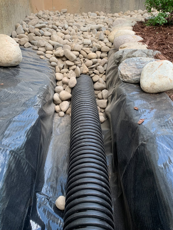 DIY drainage installation pictures for water outside a home. Exterior foundation french drain system and underground downspout drainage ideas. How to install a french drain stone landscape bed around a house and burying gutter downspout drain pipe. Drainage ideas for french drains, downspouts, catch basins, and plumbing pipes.